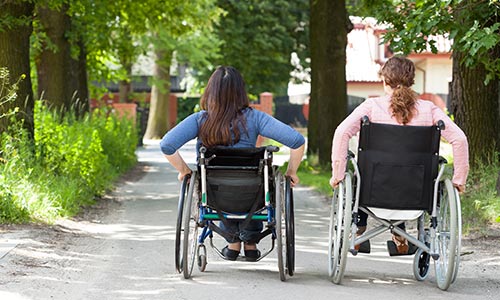 Two women in wheelchairs moving away from the viewer.