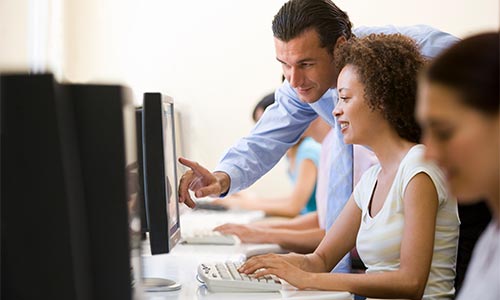 Hombre que ofrece formación a una mujer en una computadora.